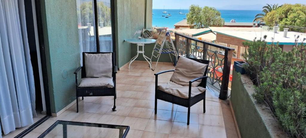 a balcony with two chairs and a table and the ocean at Borde Mar Costa Papudo in Papudo