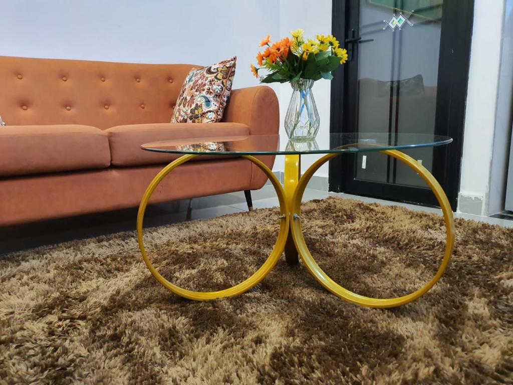 a glass coffee table with a yellow frame in front of a couch at Khomes cosy studio in Nairobi