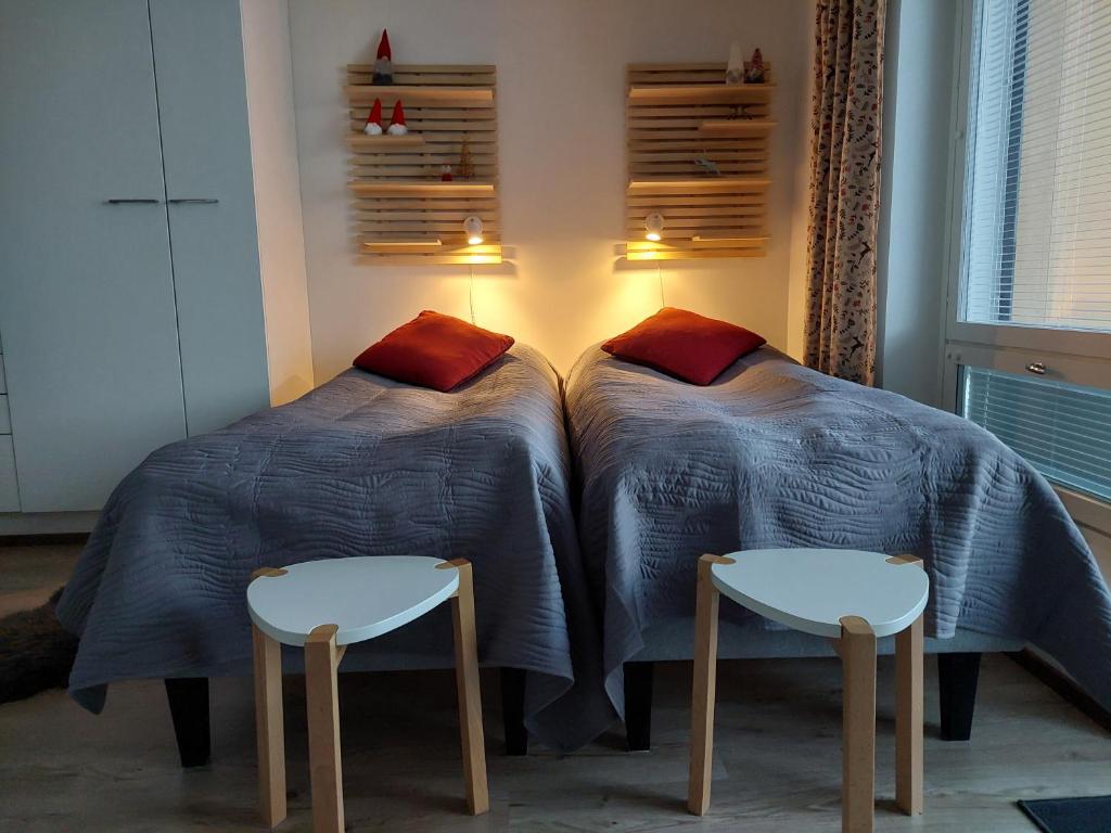 twee bedden in een kamer met twee stoelen ernaast bij Arctic Aurora Luxury, Lehtikatu 2A 96100 Rovaniemi in Rovaniemi