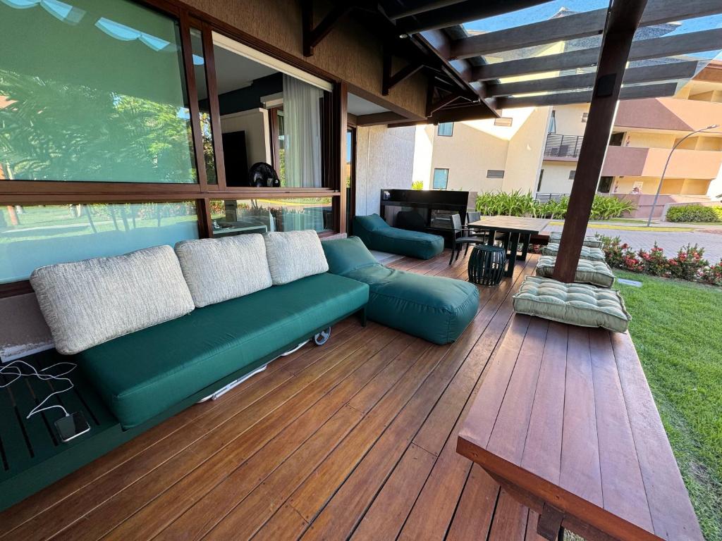 a patio with a green couch on a wooden deck at Flat+deck ao lado da igrejinha in Praia dos Carneiros