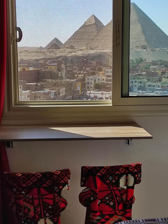 a window with two chairs looking out at the pyramids at pyramids view suite/vista piramidi in Cairo