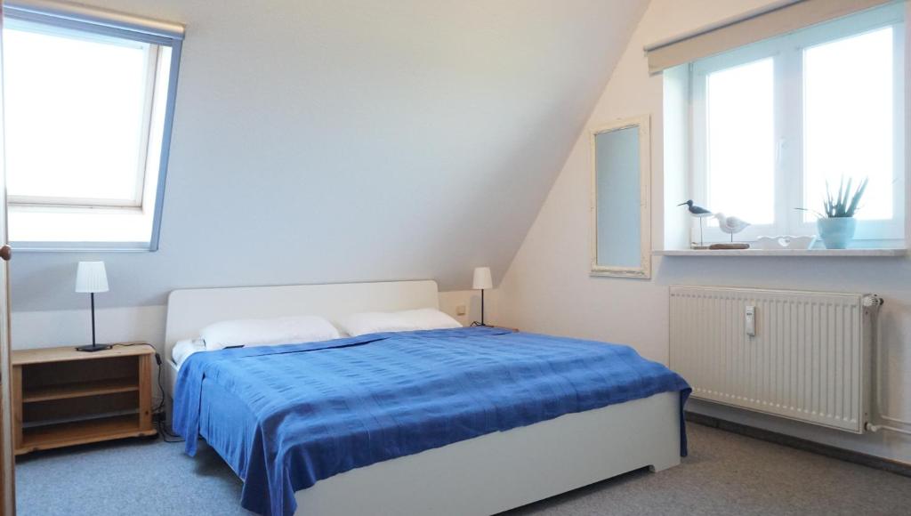 - une chambre avec un lit avec une couverture bleue et 2 fenêtres dans l'établissement Ankerplatz, à Garding