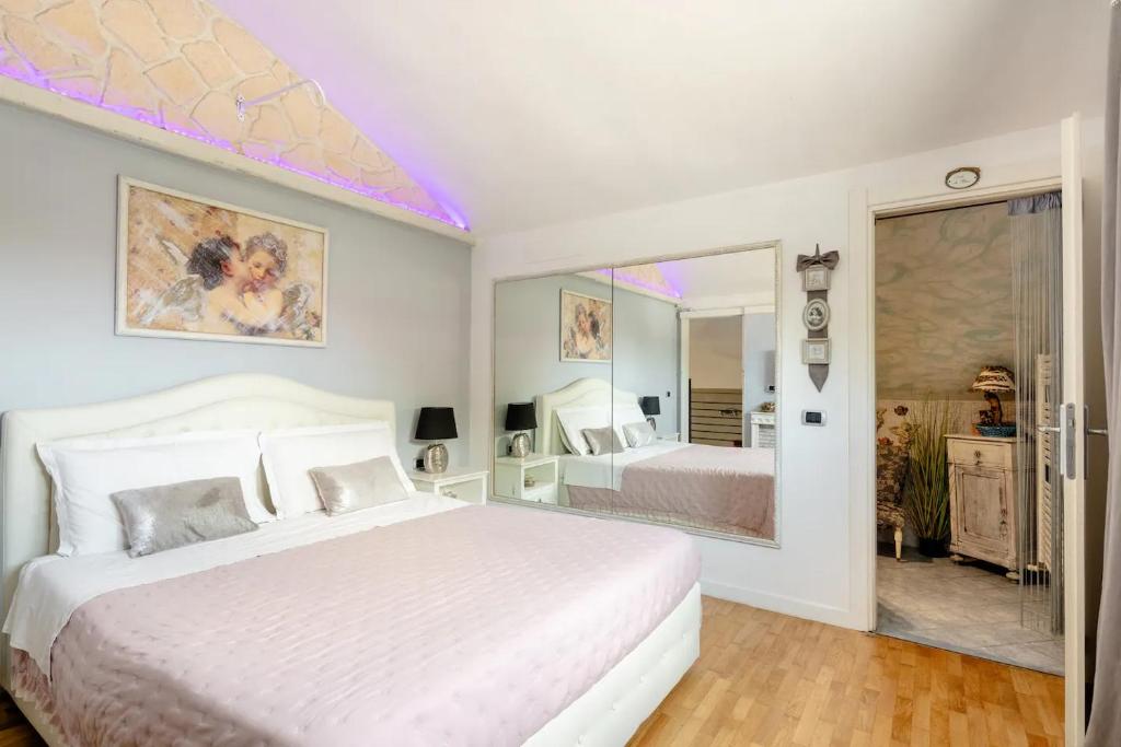 1 dormitorio con 1 cama blanca grande y espejo en Garden Loft, en Baricella