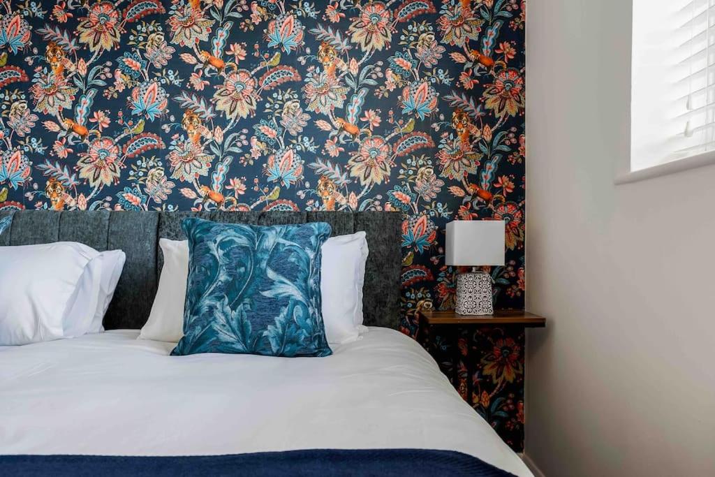 um quarto com uma cama com papel de parede floral em 2 bedroom House-Driveway - Bournemouth Hospital - Long Stay Discounts - Lima Apartments Ltd em Bournemouth