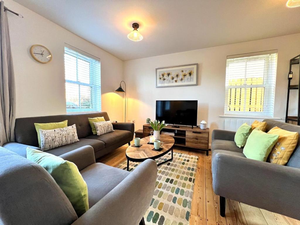 ein Wohnzimmer mit zwei Sofas und einem Fernseher in der Unterkunft Cosy Cotswold Home - Jacobs Cottage in Cirencester