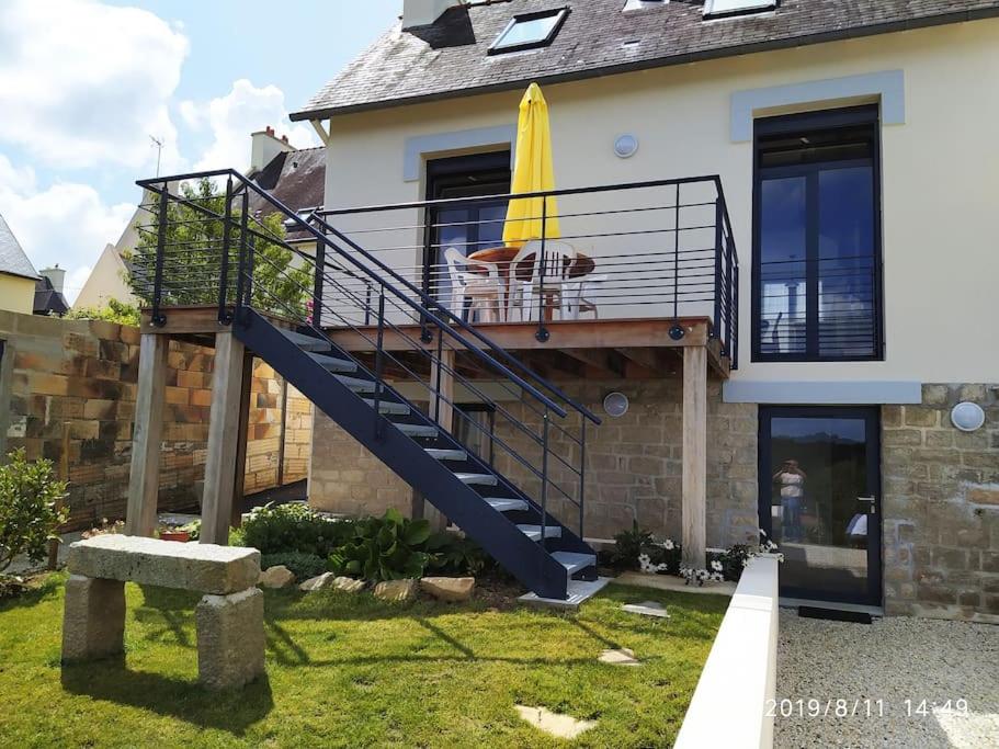 a dog sitting on a balcony with a yellow umbrella at Maison rénovée atypique, jardin, terrasse, Odet in Quimper