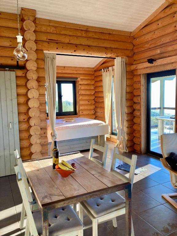 a dining room with a table and a bed in a log cabin at Private Mountain Log Cabin with amazing panoramic sunset views at small scale nature resort in Cabeceiras de Basto