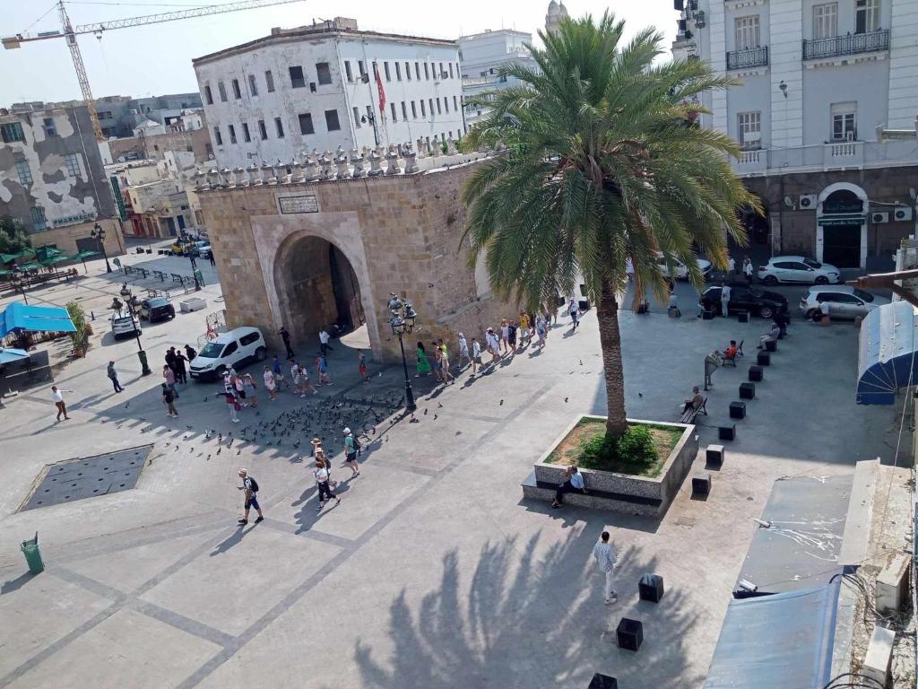 un grupo de personas caminando por una ciudad con una palmera en Hotel Marhaba - Beb Bhar Tunis en Túnez