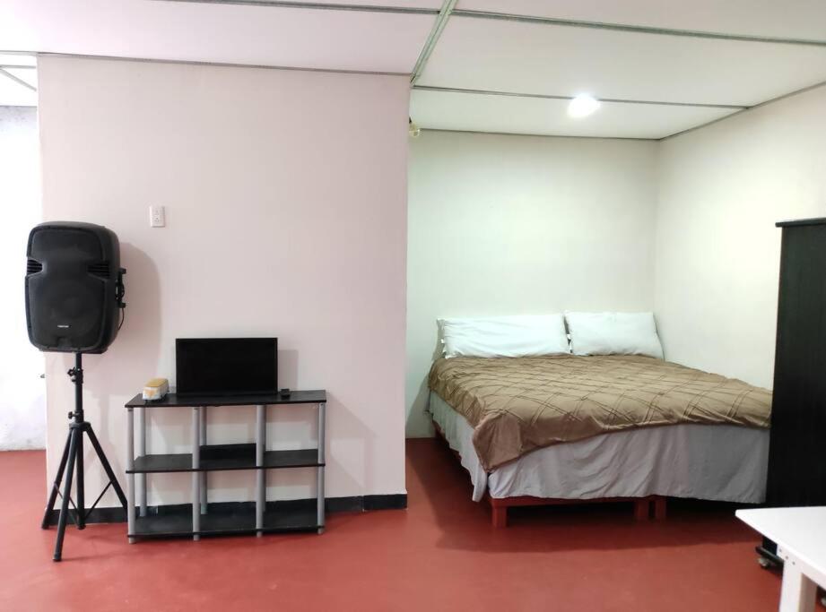 um quarto com uma cama e uma televisão num quarto em Casa Sandunga em Oaxaca de Juárez