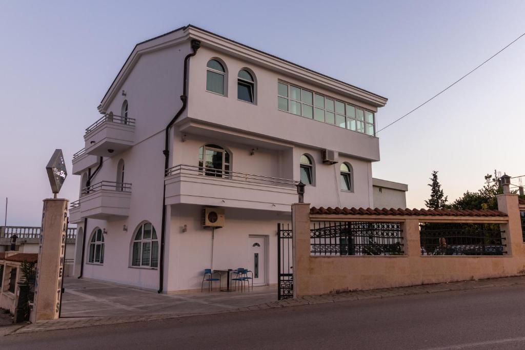 a white house with a fence in front of it at Blue Sky Apartments-Ulcinj, Montenegro in Ulcinj