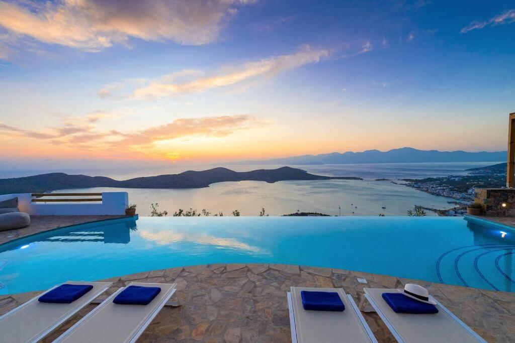 a pool with a view of the ocean at sunset at Luxury Villa Orea, Elounda (owner's listing) in Epáno Eloúnda