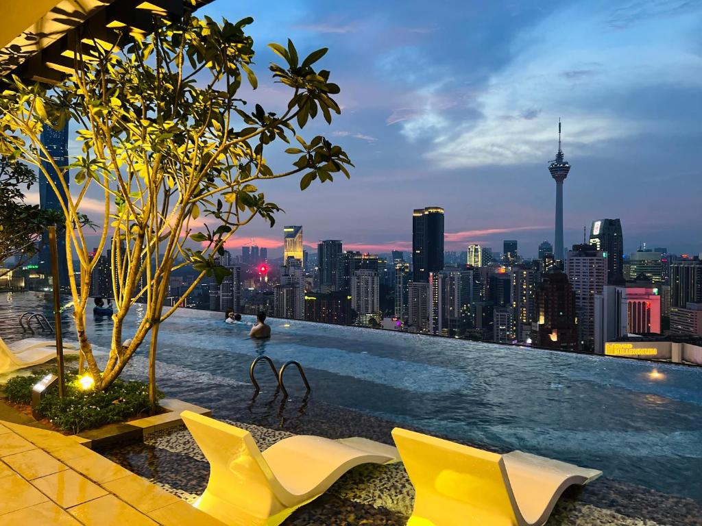 a swimming pool with chairs and a city skyline at AXON RESIDENCE KLCC BY JD in Kuala Lumpur