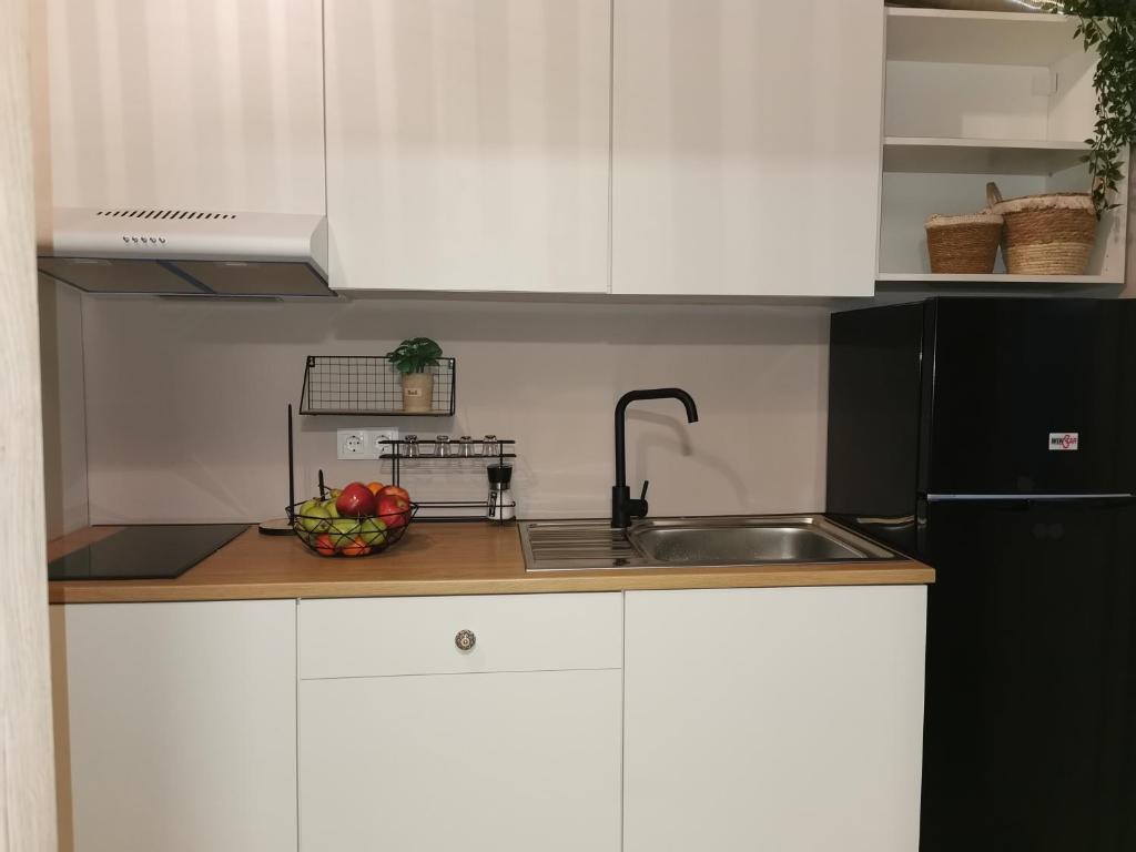 uma cozinha com armários brancos, um lavatório e uma taça de fruta em Boho Sisi Resort em Sissi