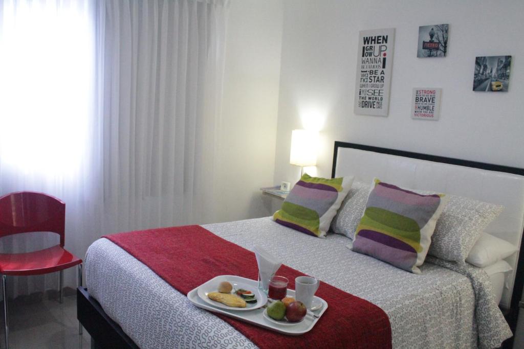 a bedroom with a bed with a tray of food on it at Hotel Golden House in Barranquilla