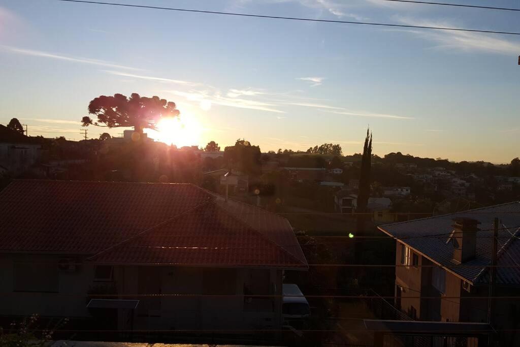 una puesta de sol sobre una ciudad con casas y un árbol en Casa aconchegante e tranquila, em Veranópolis/RS., en Veranópolis