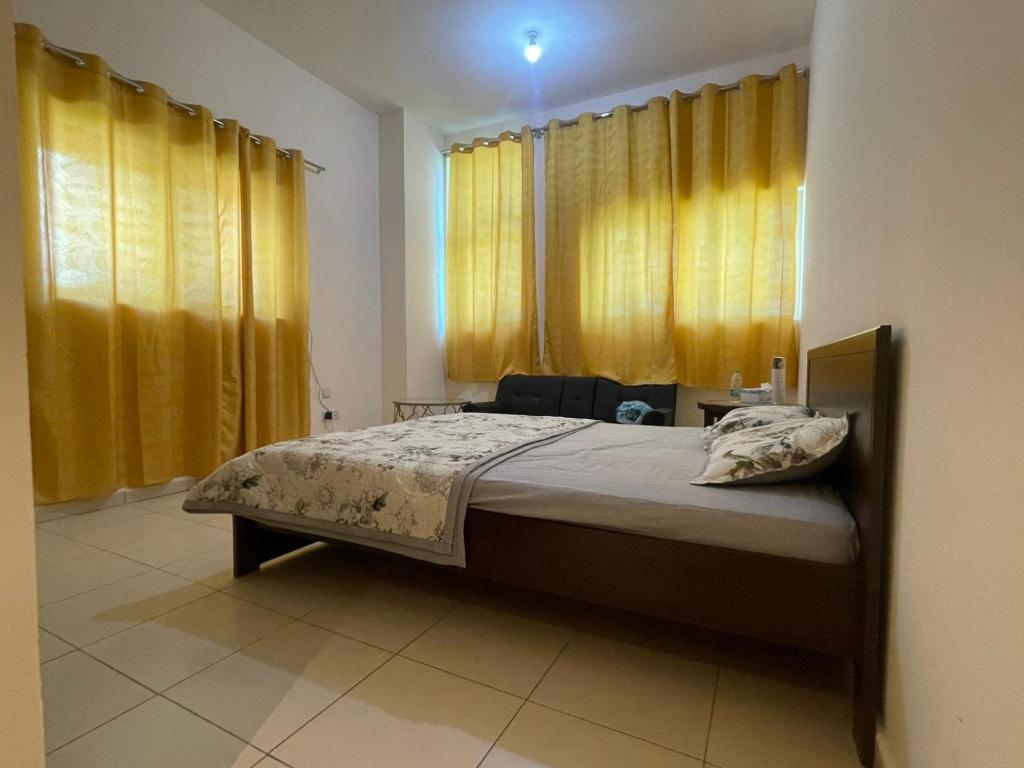 um quarto com uma cama grande e cortinas amarelas em Holiday Home Master bed room in Ajman city UAE em Ajman