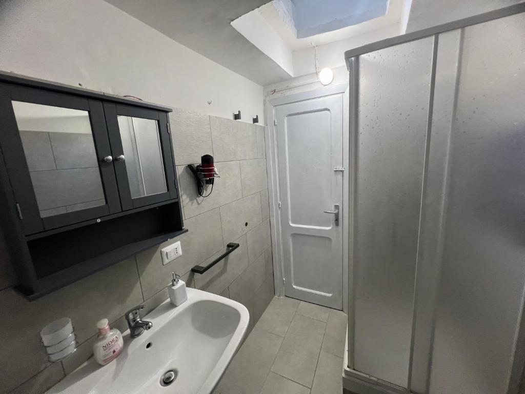 een badkamer met een wastafel en een douche met een glazen deur bij Domus Isidis room in Benevento