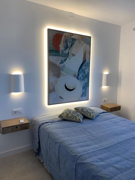 Un dormitorio con una cama azul con una pintura en la pared en apartamento nº 7 cala pregonda en Cala Blanca