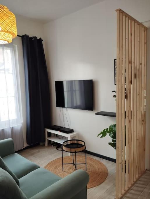 a living room with a couch and a tv on a wall at Le Studio de la Seine in Elbeuf