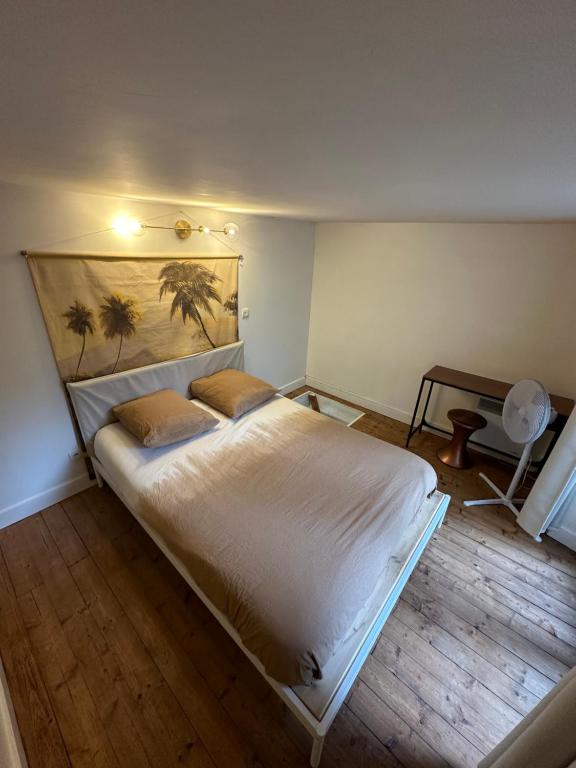 1 dormitorio con 1 cama blanca y una pintura en la pared en Le petit Championnet T2 en Grenoble