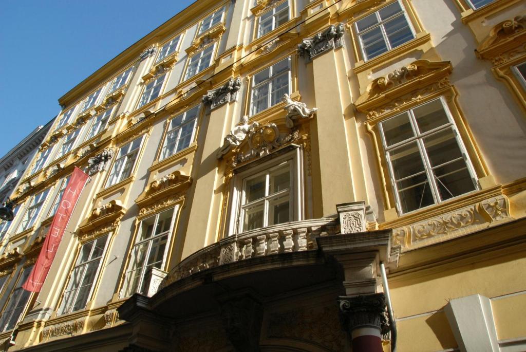 a yellow building with windows and a balcony at Pertschy Palais Hotel in Vienna