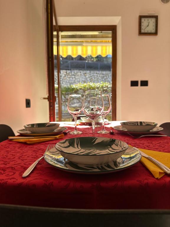 a table with plates and wine glasses on a red table cloth at Casa Vacanza La Croseta in Trento