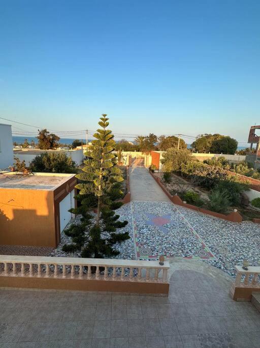 uma vista para um jardim com uma árvore numa rua em Villa spacieuse 200 m à la plage em Zarzis
