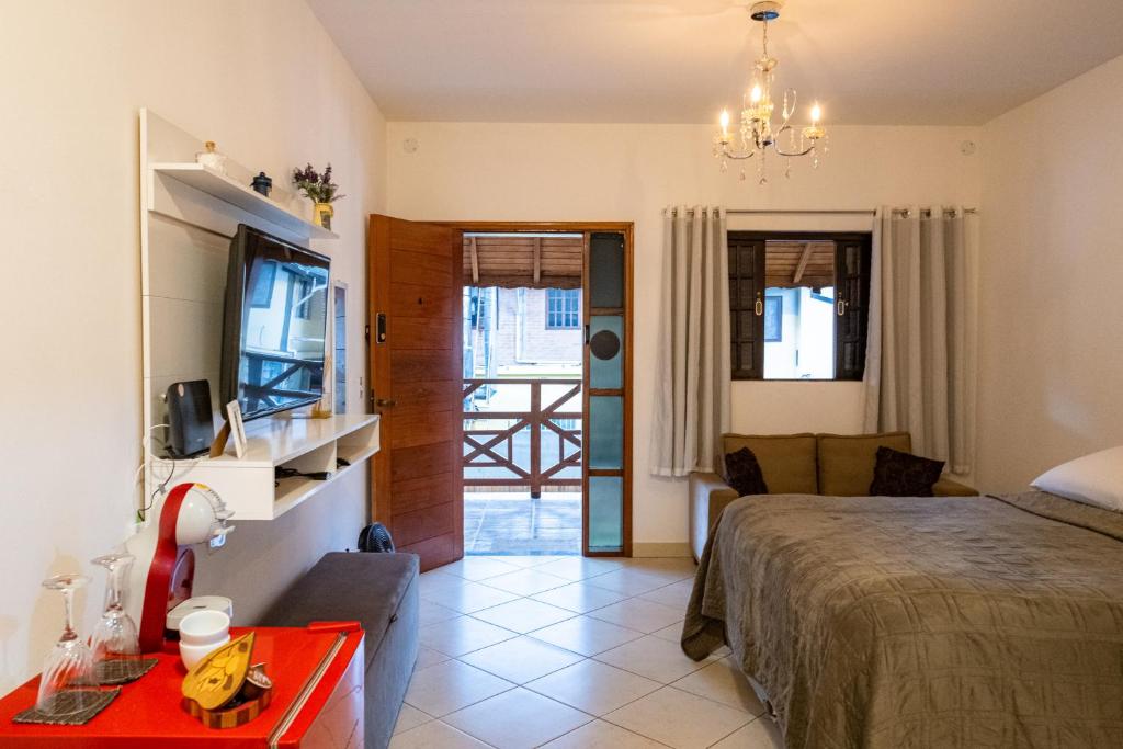 um quarto com uma cama e uma sala de estar em Apartamento Le Quatre Centro Monte Verde em Monte Verde