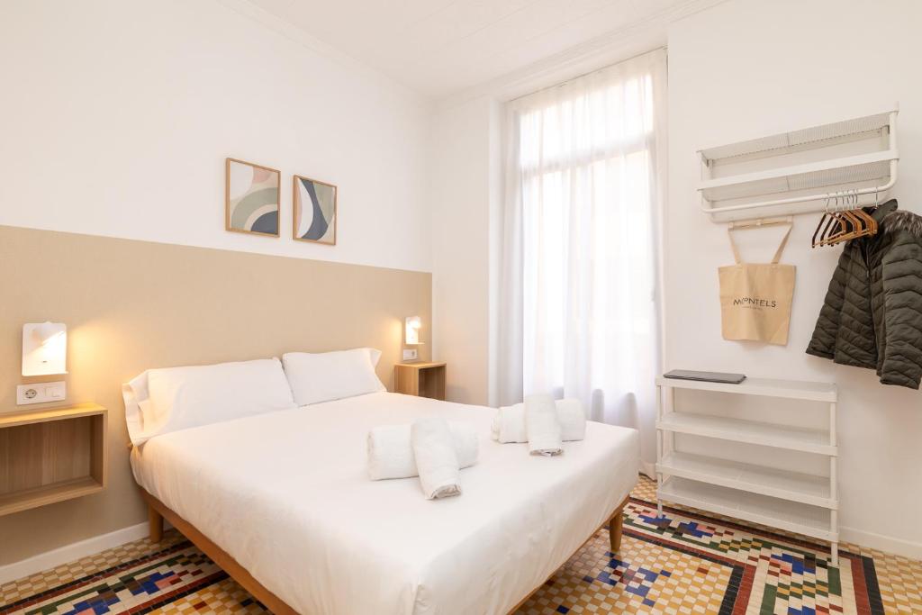 a white bedroom with a bed and a window at Pensión Alicante by Moontels in Valencia