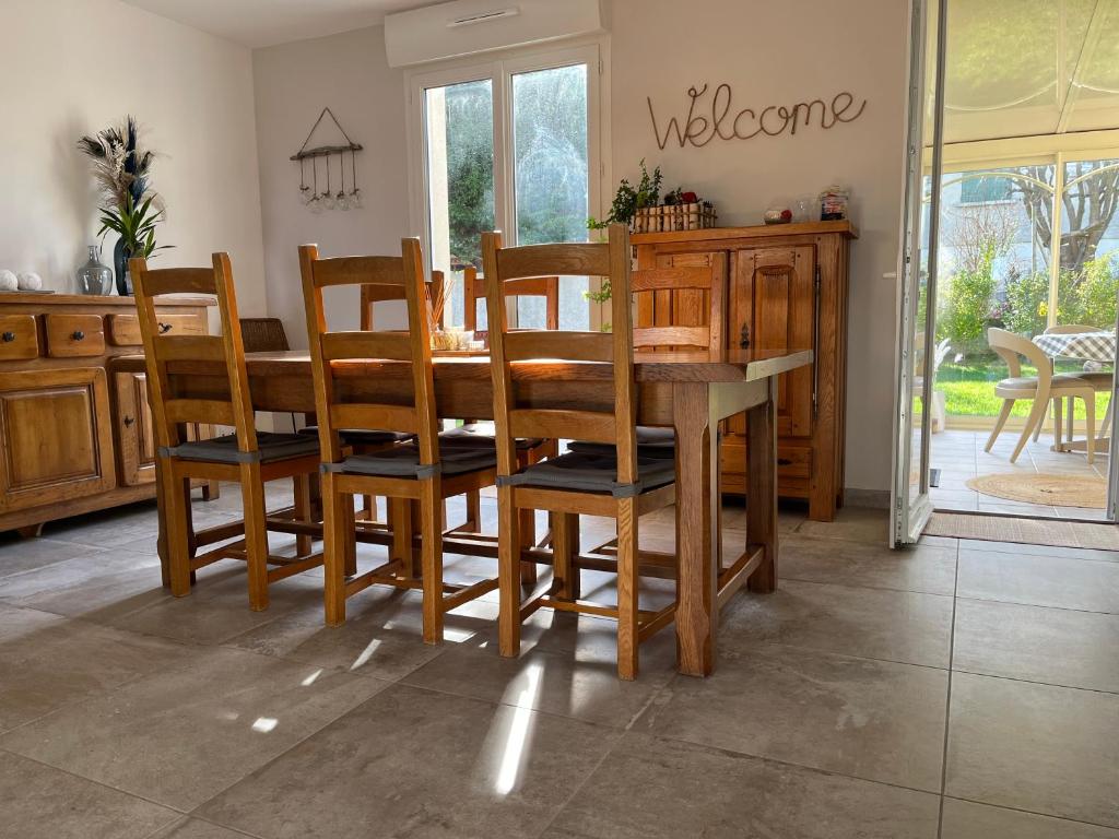 ein Esszimmer mit einem Holztisch und Stühlen in der Unterkunft Maison plain-pied 4 chambres Graye sur mer plage à 700 m in Graye-sur-Mer