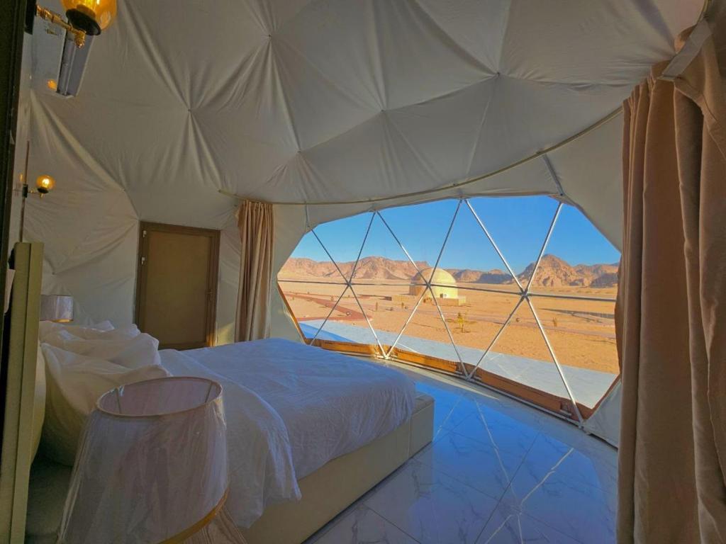 a bed in a tent with a view of the desert at Wadi rum anwar luxury camp in Wadi Rum