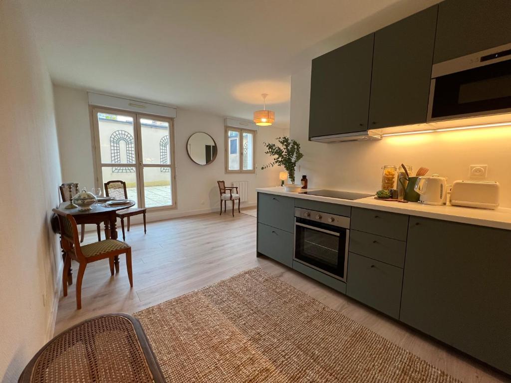 a kitchen with green cabinets and a dining room at Terrasse coeur de Vendôme Caroline Paul Officiel in Vendôme