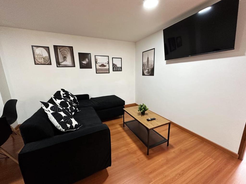 ein Wohnzimmer mit einem schwarzen Sofa und einem Tisch in der Unterkunft Apartamento céntrico frente a la Javeriana en el corazón de Bogotá in Bogotá