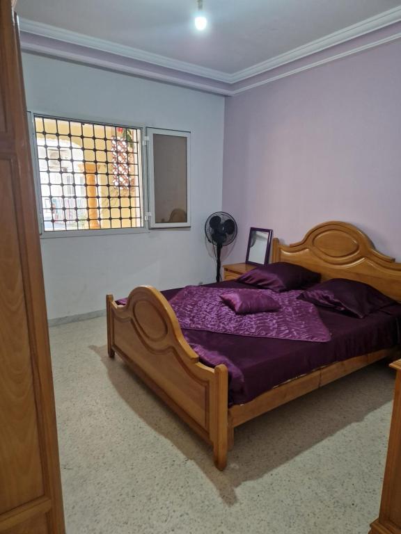 a bedroom with a bed with purple sheets and a window at Apparemment tabarka in El Aouina
