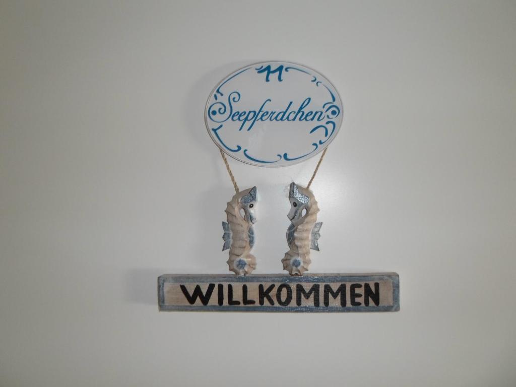 a sign that says willkommen with two people holding a balloon at Seepferdchen in der Villa Medici in Norderney