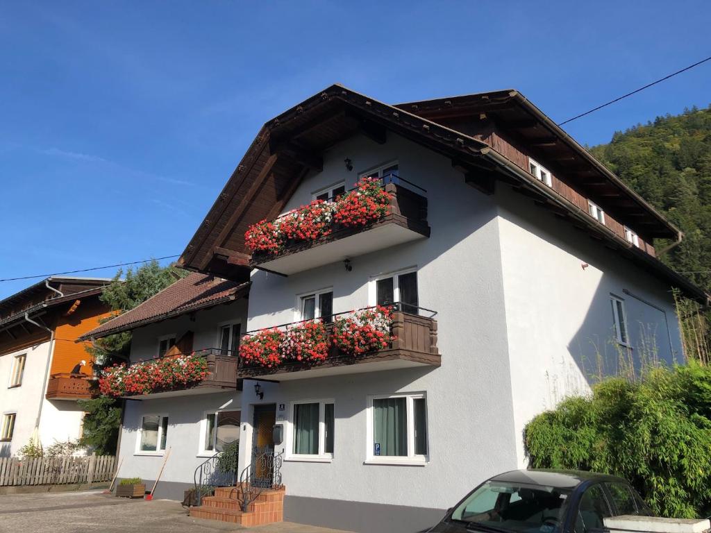 um edifício branco com caixas de flores em Appartement Brettljause Ferienhaus Fuenf Sinne em Döbriach