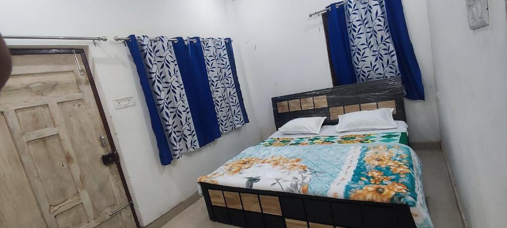 a bedroom with a bed with blue curtains and a door at IK Homestay in Varanasi