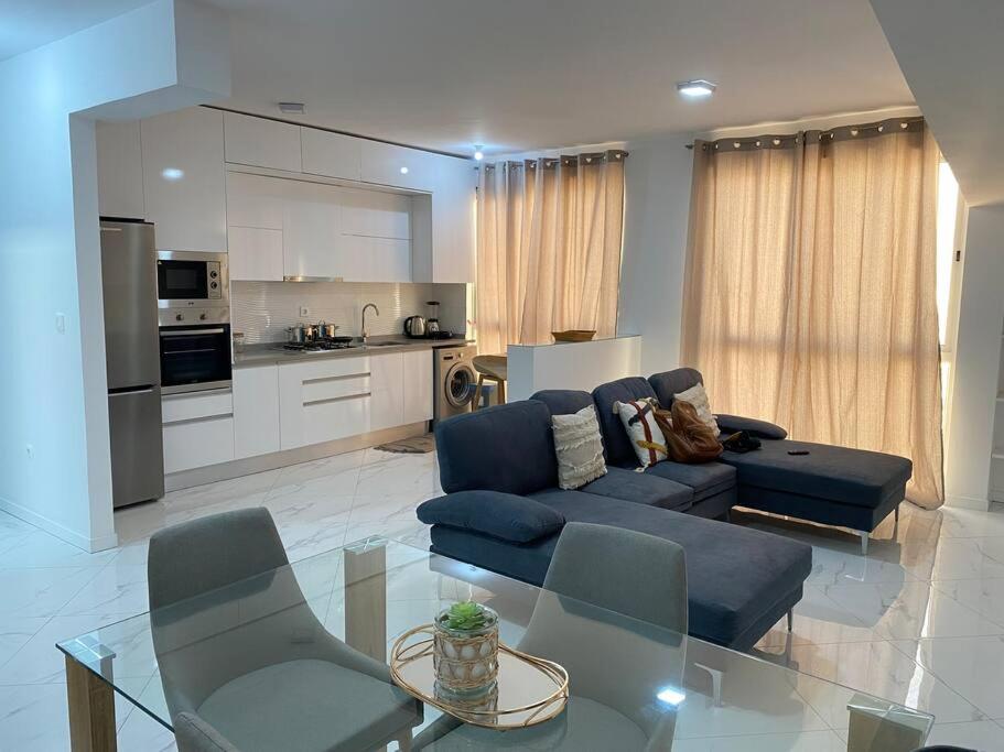 uma sala de estar com um sofá azul e uma mesa de vidro em Apartamento sublime c/vista top. em Praia
