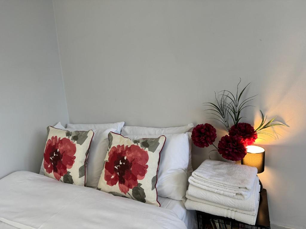 eine weiße Couch mit Kissen und Blumen darauf in der Unterkunft Surbiton Home with free parkings, Surbiton, Kingston upon Thames, Surrey, Greater London UK in Surbiton