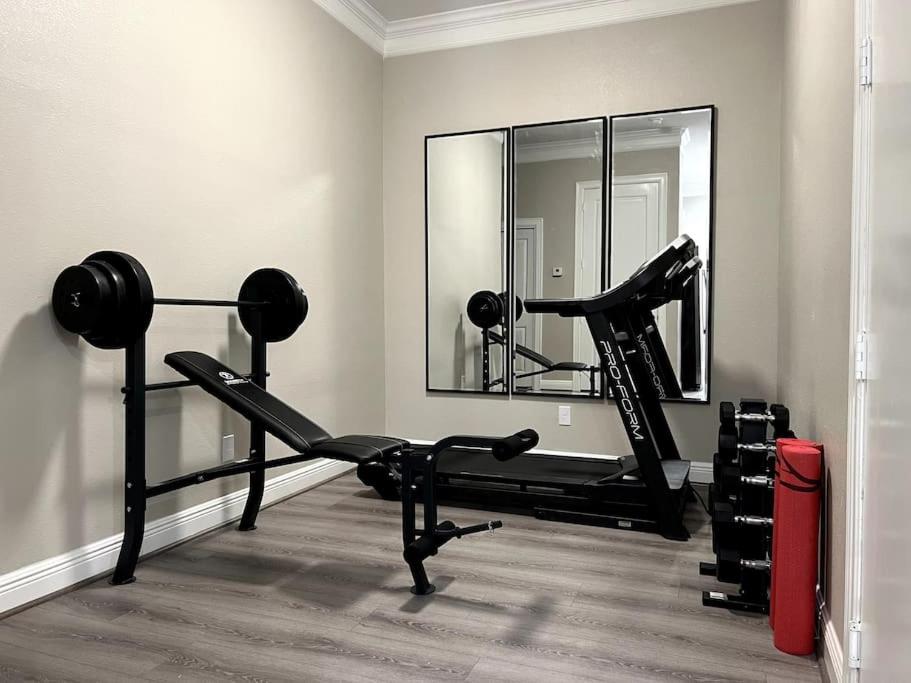 ein Zimmer mit einem Fitnessraum mit einem Spiegel und einem Laufband in der Unterkunft Pet OK, 10 min to Alphaland, Home Gym, Gated in Houston