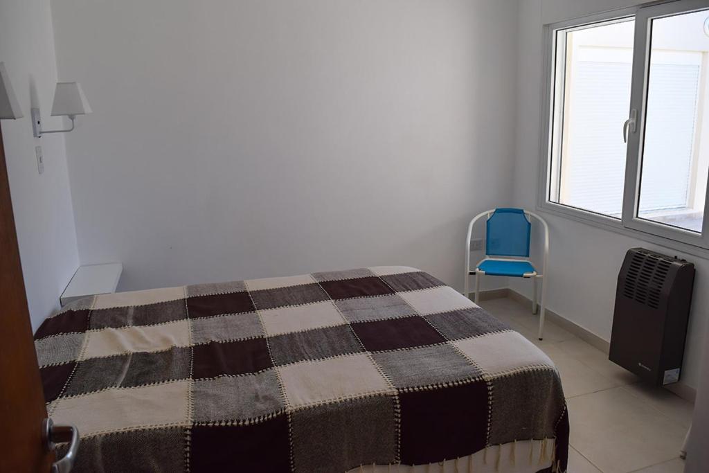 ein Schlafzimmer mit einem Bett und einem blauen Stuhl in der Unterkunft Las Ballenas Casas de Playa - frente al mar in Monte Hermoso