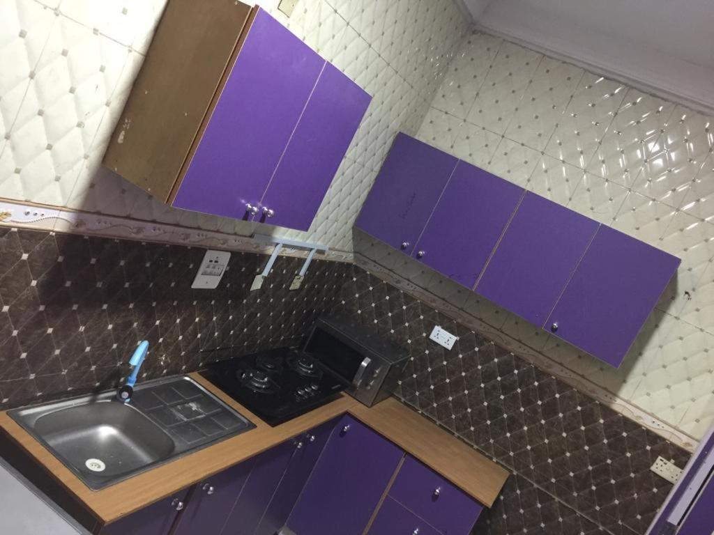 a small kitchen with purple cabinets and a sink at Mega Pavilion Apartment And Suits Gwarinpa in Gwarinpa