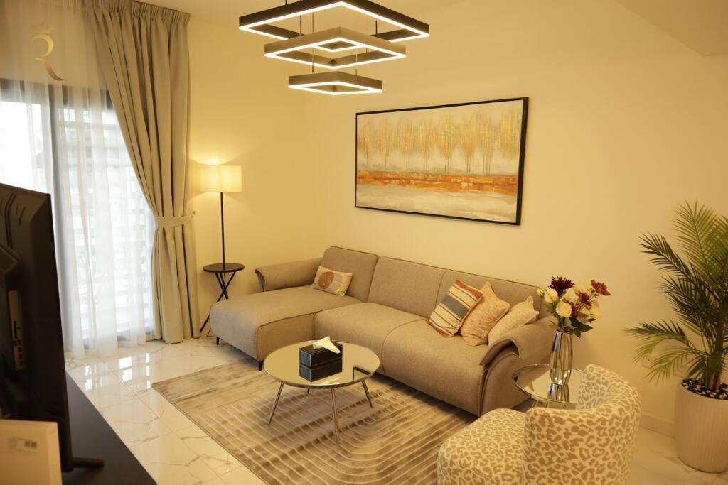 a living room with a couch and a table at Amber Glow 2BR Apartment Al Raha in Abu Dhabi
