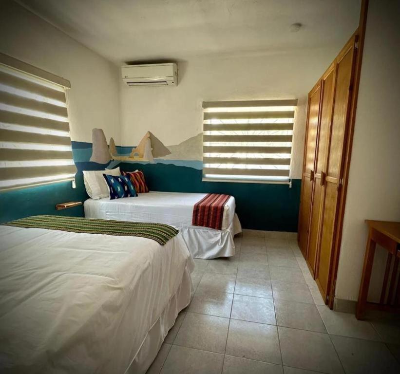 a hotel room with two beds and two windows at Baja Real Hotel Boutique in La Paz