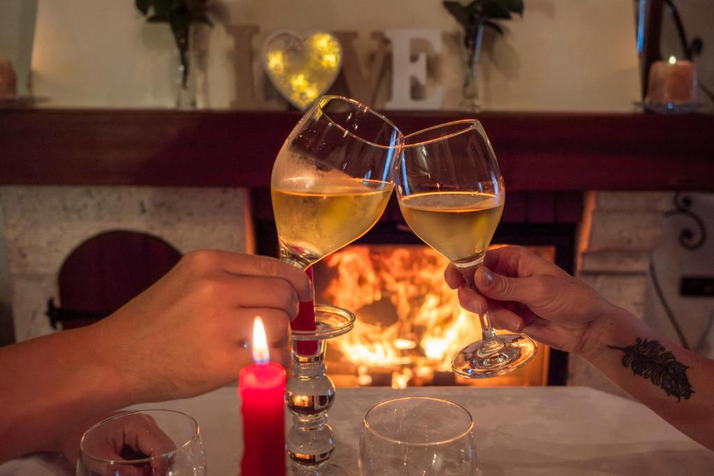 two people holding glasses of wine in front of a fire at Casa do Sear - Turismo Rural & Spa Exterior in Sanxenxo