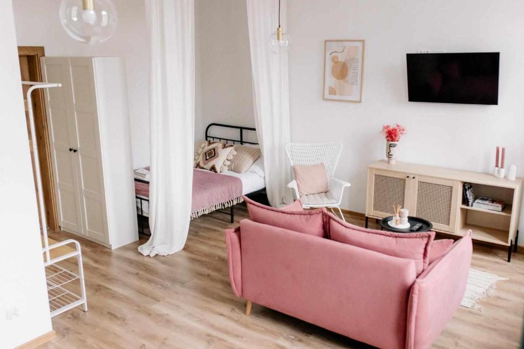 ein Wohnzimmer mit 2 rosa Stühlen und einem Bett in der Unterkunft Apartament Pastelowy Kwidzyn in Kwidzyn