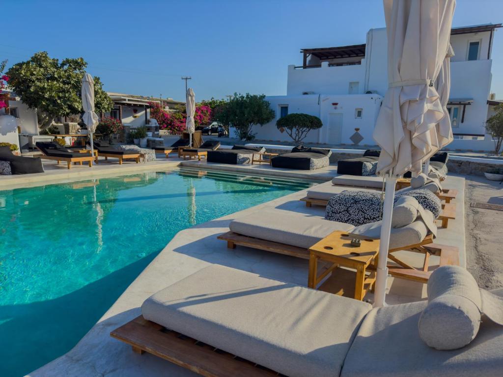 a swimming pool with chaise lounges and umbrellas at Irene's Residence in Mikonos