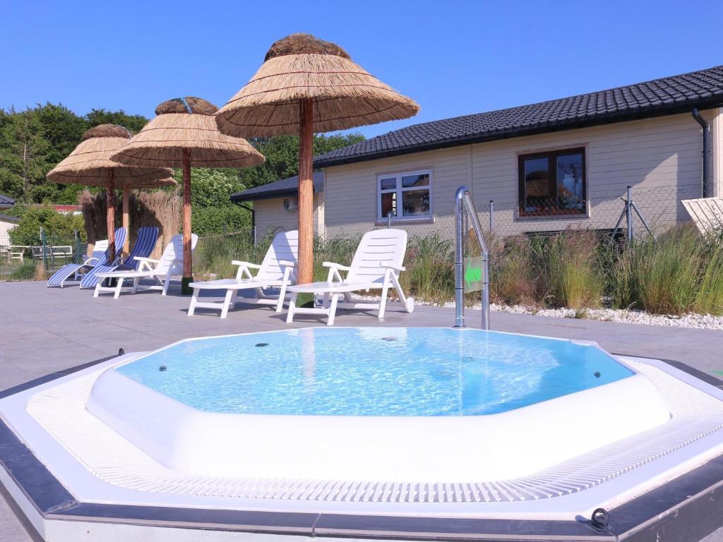 einen Whirlpool mit Stühlen und Sonnenschirmen auf einer Terrasse in der Unterkunft Holiday house for 4 people, pool, sauna, Ustronie in Ustronie Morskie