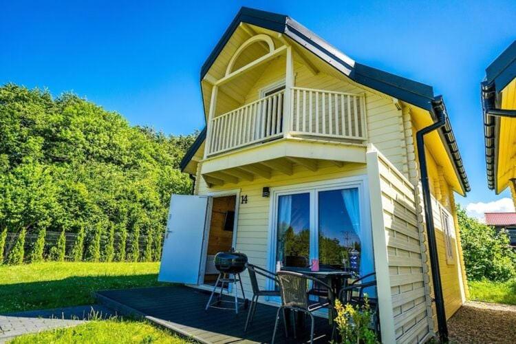 a small yellow house with a balcony and a table at Holiday resort with Pool Whirlpool Sauna Ustronie Morskie in Ustronie Morskie