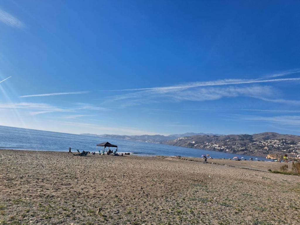 a beach with a group of people sitting on the beach at Atico TERRAZA DEL CARMEN in Salobreña